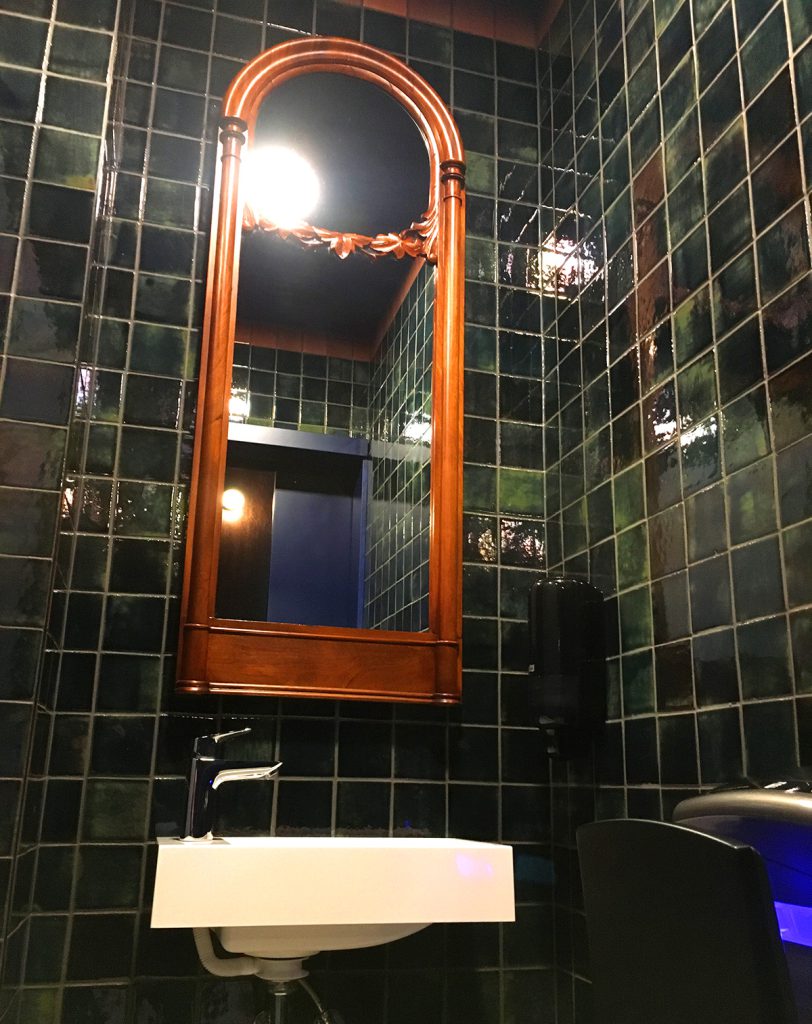 Łazienka w zielonych płytkach ściennych z lustrem retro.